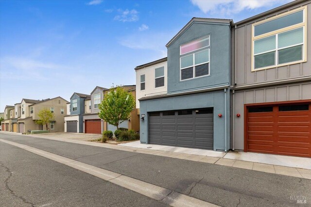 multi unit property featuring a residential view, board and batten siding, an attached garage, and stucco siding