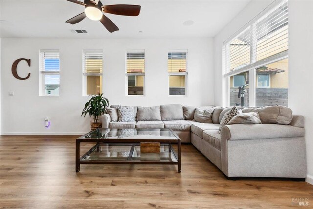 living area featuring baseboards, a ceiling fan, wood finished floors, and visible vents
