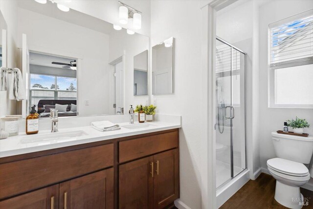 ensuite bathroom featuring a ceiling fan, a sink, toilet, and a shower stall