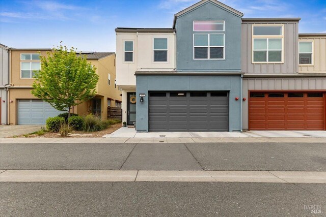 townhome / multi-family property with board and batten siding, an attached garage, and stucco siding