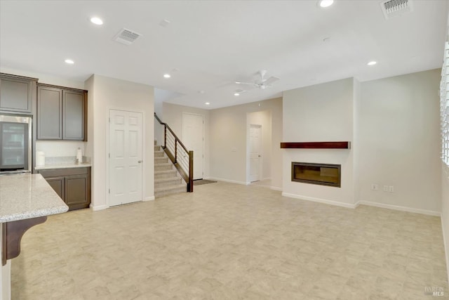unfurnished living room featuring visible vents, recessed lighting, stairs, and ceiling fan