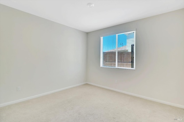 empty room with baseboards and light carpet