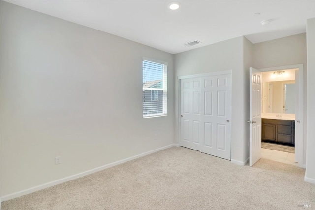 unfurnished bedroom featuring baseboards, light colored carpet, and visible vents