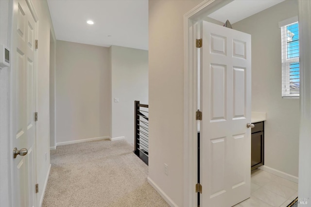 hall with baseboards, light carpet, and an upstairs landing