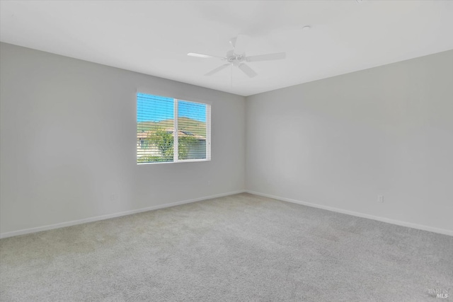 carpeted spare room with baseboards and a ceiling fan