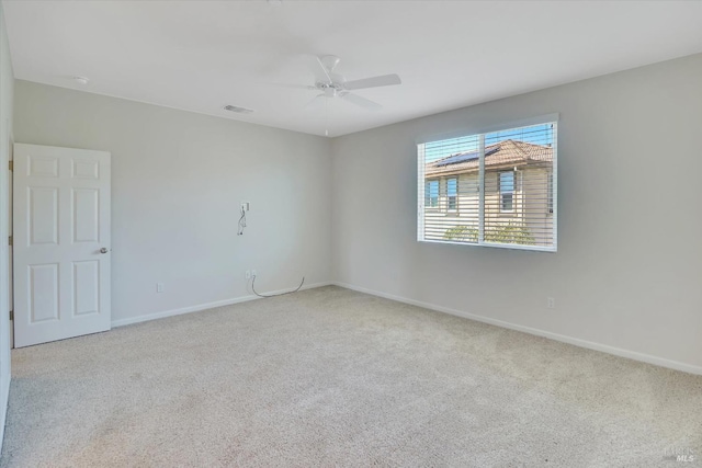 carpeted spare room with baseboards, ceiling fan, and visible vents