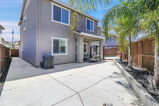 back of property with cooling unit, a fenced backyard, a patio area, and stucco siding