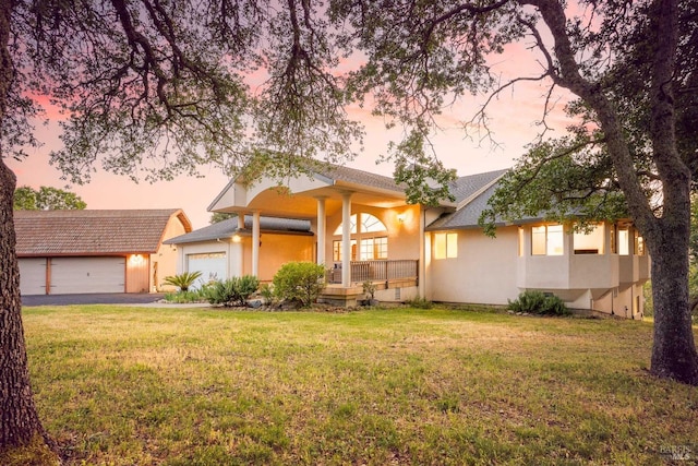 view of front of home featuring an attached garage, a front yard, stucco siding, a porch, and driveway