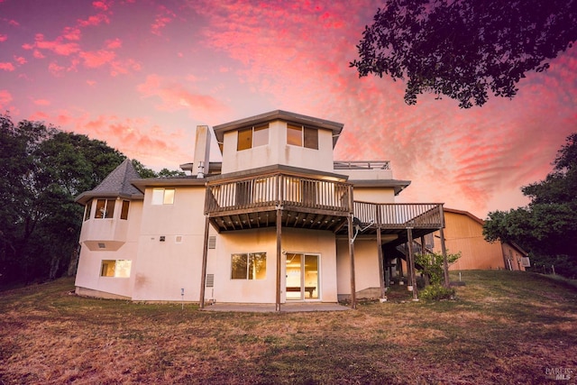 back of property with a lawn, stucco siding, a patio area, and a deck