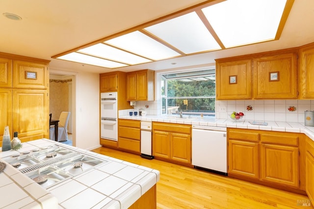 kitchen with white appliances, brown cabinets, decorative backsplash, and light wood-type flooring