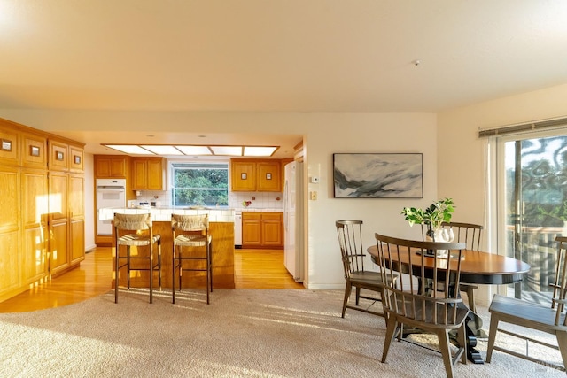 dining room with light colored carpet, baseboards, and light wood-type flooring