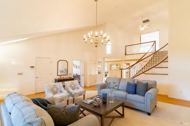 living area with light wood-style floors, high vaulted ceiling, stairs, baseboards, and visible vents