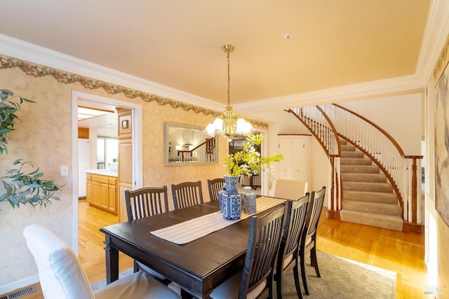dining area featuring visible vents, light wood-type flooring, stairway, an inviting chandelier, and wallpapered walls