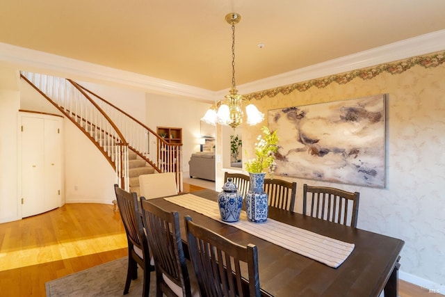 dining room with crown molding, wood finished floors, baseboards, a chandelier, and stairs