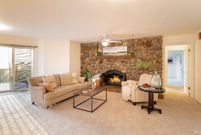 carpeted living room featuring ceiling fan, visible vents, and a stone fireplace