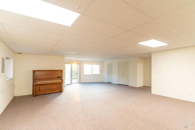 basement with light colored carpet and a paneled ceiling