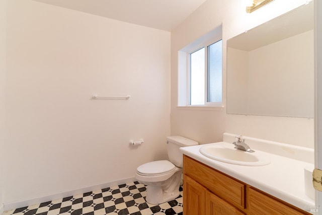 half bath featuring vanity, baseboards, tile patterned floors, and toilet