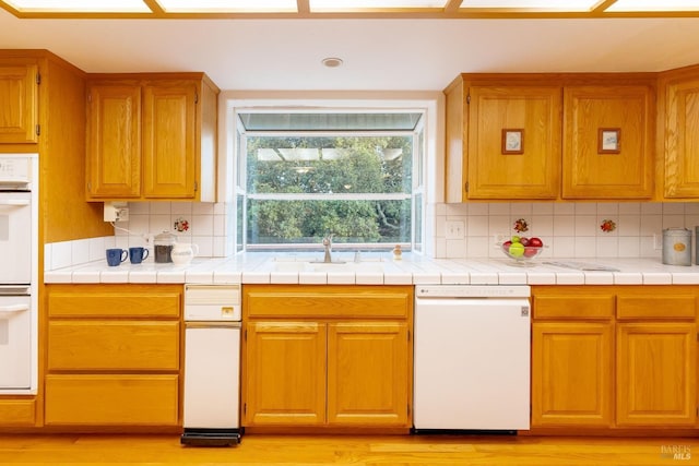kitchen with tasteful backsplash, white appliances, and light wood-style flooring