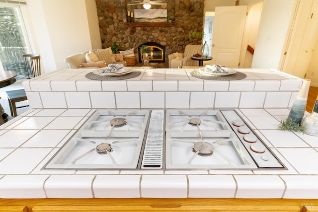 interior details with tile counters and a stone fireplace