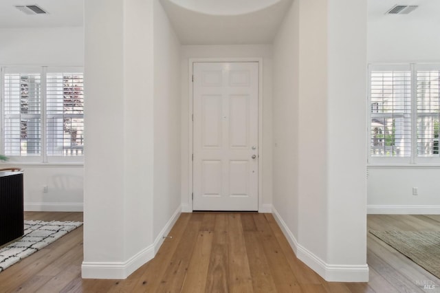 hallway featuring a healthy amount of sunlight, light wood-style flooring, and visible vents