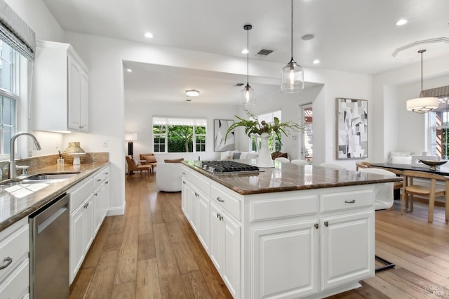 kitchen with appliances with stainless steel finishes, a sink, visible vents, and light wood-style floors