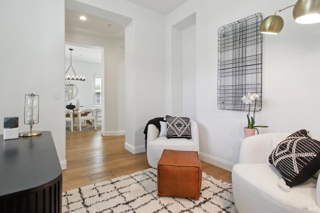 living area featuring an inviting chandelier, baseboards, and wood finished floors