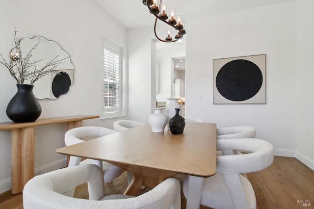 dining space featuring baseboards, wood finished floors, and a chandelier