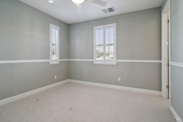 carpeted spare room with visible vents, plenty of natural light, ceiling fan, and baseboards