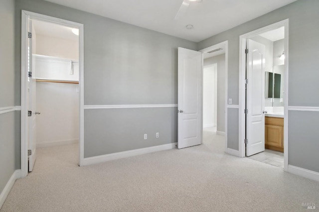 unfurnished bedroom with a spacious closet, baseboards, a closet, and light colored carpet