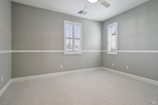 carpeted spare room with ceiling fan, visible vents, plenty of natural light, and baseboards