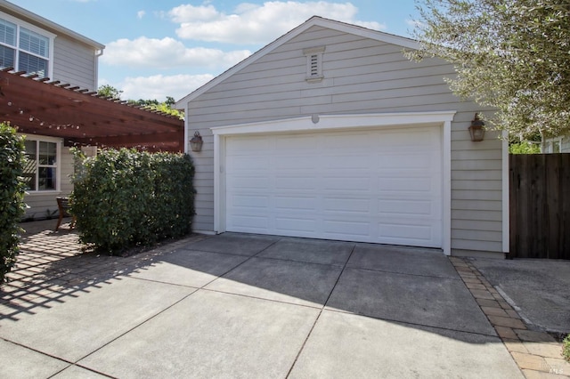 garage featuring fence and concrete driveway