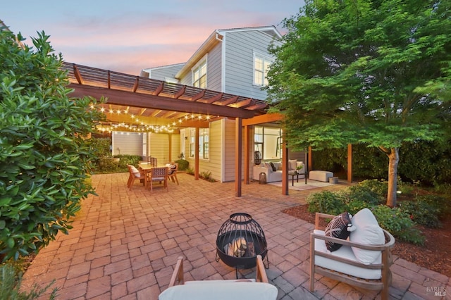 patio terrace at dusk with a pergola, outdoor dining area, and an outdoor fire pit