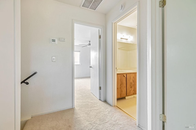 hallway featuring light colored carpet, baseboards, and visible vents