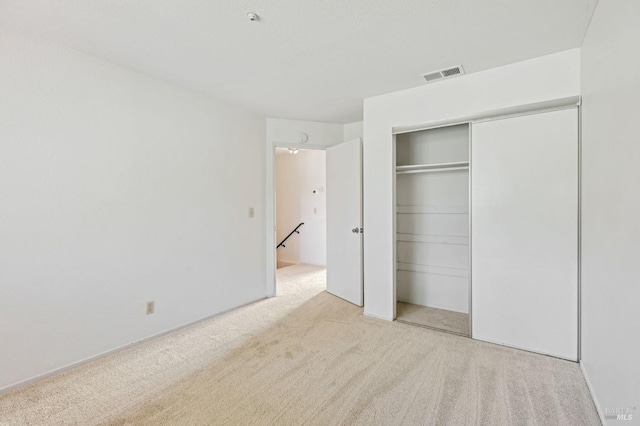 unfurnished bedroom with carpet floors, a closet, and visible vents