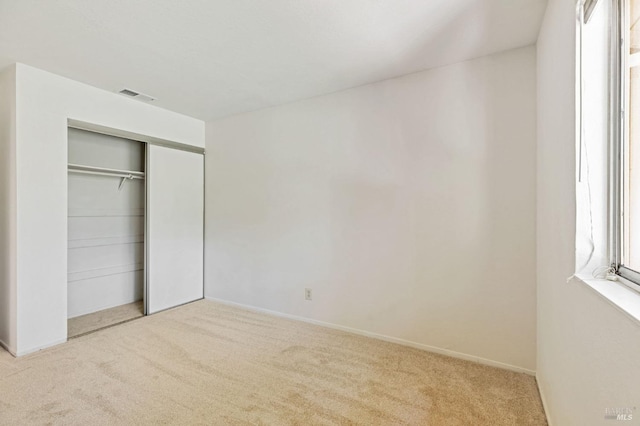 unfurnished bedroom with visible vents, carpet, baseboards, and a closet