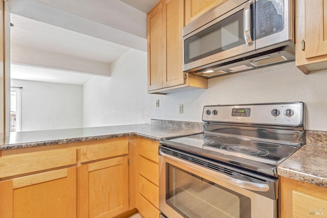 kitchen featuring light brown cabinetry, appliances with stainless steel finishes, and dark countertops