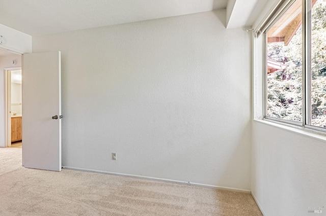 unfurnished room featuring baseboards and light colored carpet