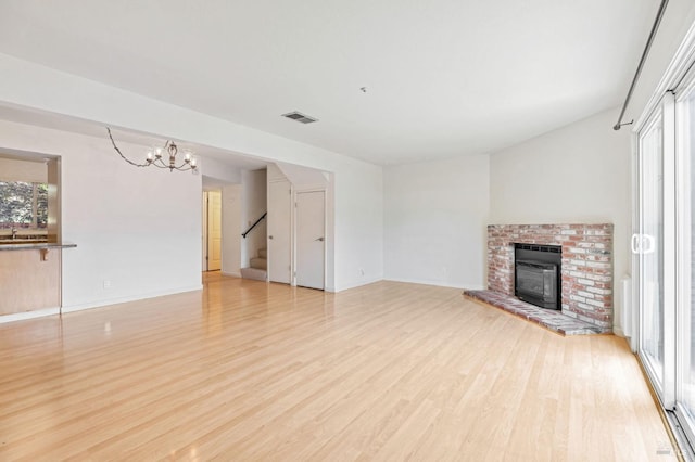 unfurnished living room featuring stairway, a wealth of natural light, light wood-type flooring, and visible vents