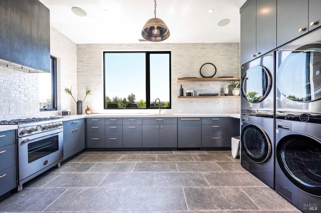 laundry area with laundry area, a sink, stacked washing maching and dryer, and stone tile flooring