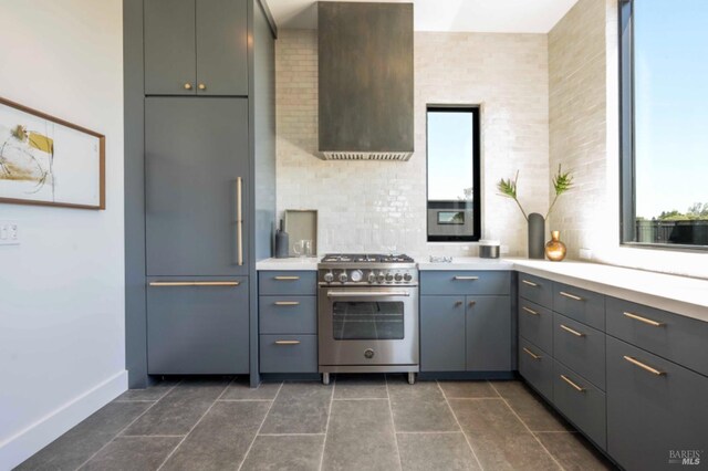 kitchen featuring baseboards, light countertops, wall chimney exhaust hood, gray cabinetry, and premium appliances