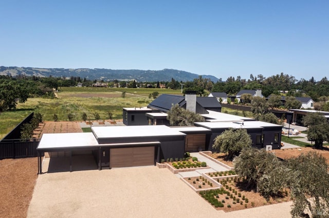 view of front of house featuring a garage, a mountain view, and gravel driveway