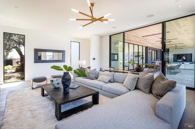 living room with plenty of natural light, wood finished floors, and a notable chandelier