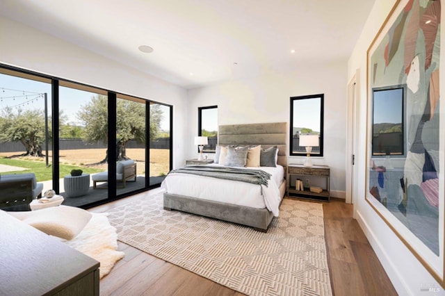 bedroom with baseboards, recessed lighting, wood finished floors, and access to exterior