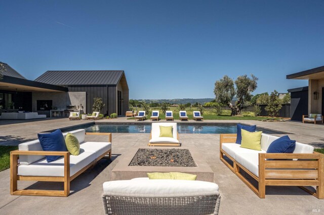 outdoor pool featuring an outdoor living space with a fire pit and a patio area