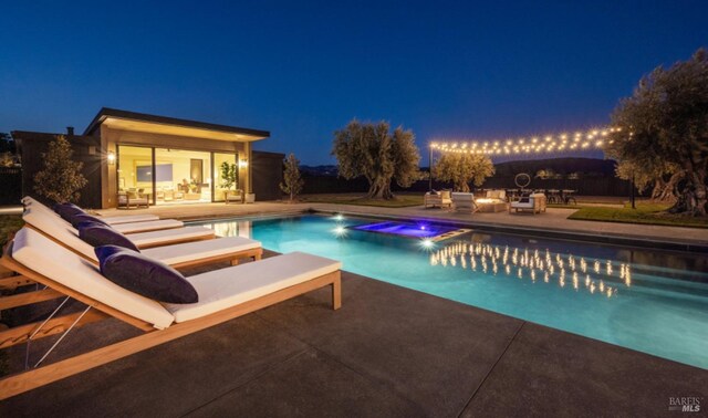 pool at twilight with an outdoor structure, a patio area, an outdoor pool, and an in ground hot tub