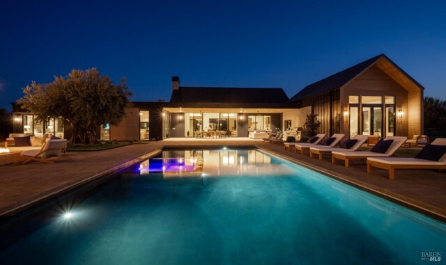 pool at twilight featuring a patio area and an outdoor pool