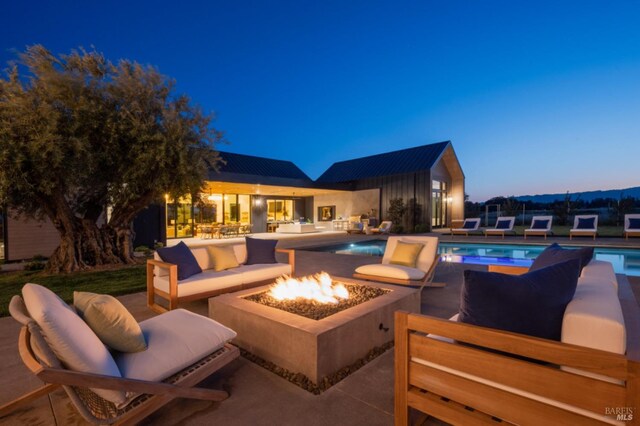 outdoor pool with a patio area and an outdoor living space with a fire pit