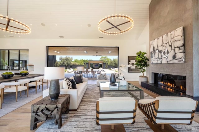living area featuring wood ceiling, a high ceiling, a fireplace, and a chandelier