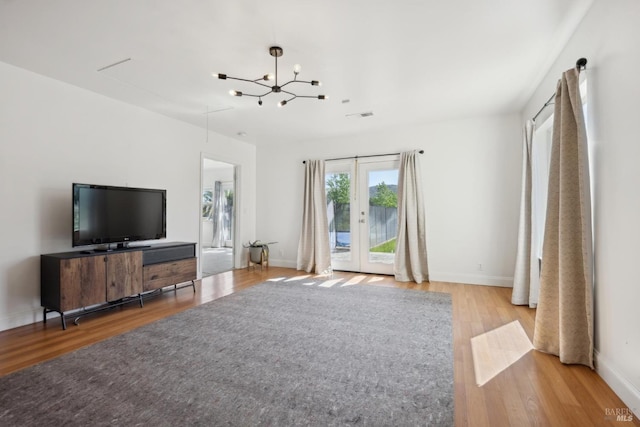 unfurnished living room with baseboards, a chandelier, and wood finished floors