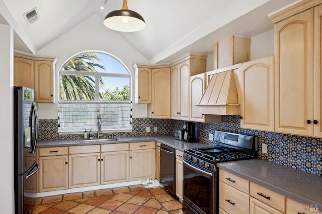 kitchen featuring light brown cabinetry, a sink, freestanding refrigerator, and gas range